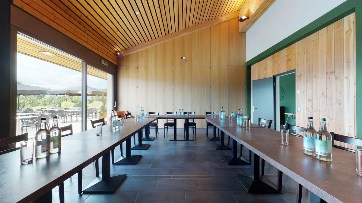 Tables disposées en U pour une réunion, ouvertes sur la terrasse