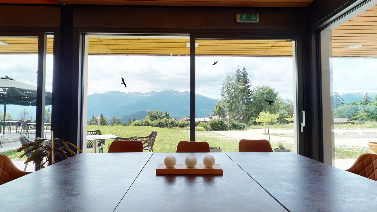 Table dressée devant une baie vitrée ouverte sur les montagnes